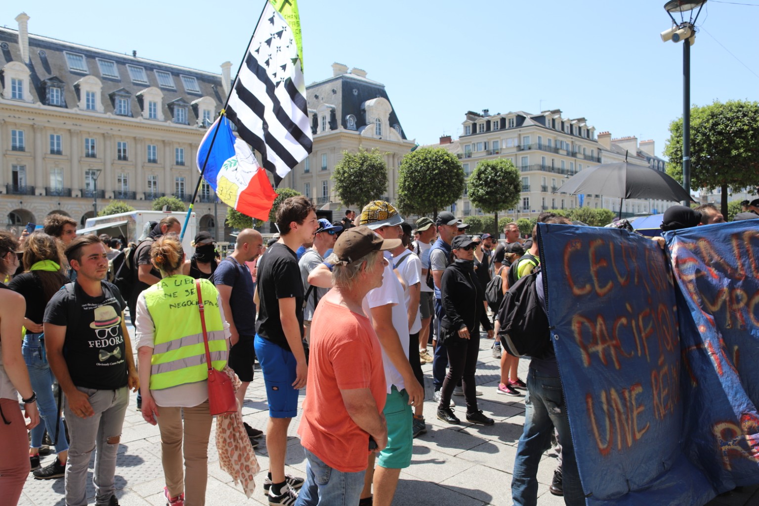 Protesters gather in a French square with Breton and French flags