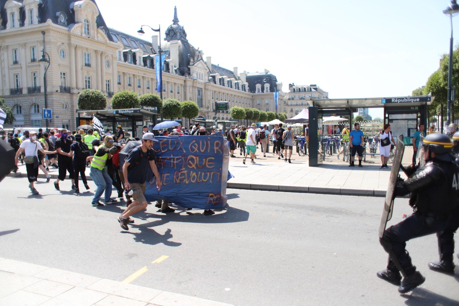 Protesters carrying a banner near République station in France as riot police stand nearby